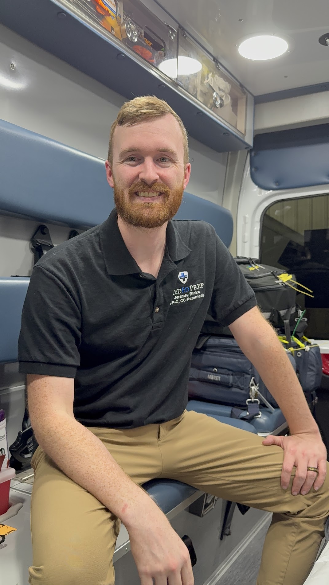 MedEdPrep founder Jeramey Ricks in a MedEdPrep polo, sitting in the back of an ambulance